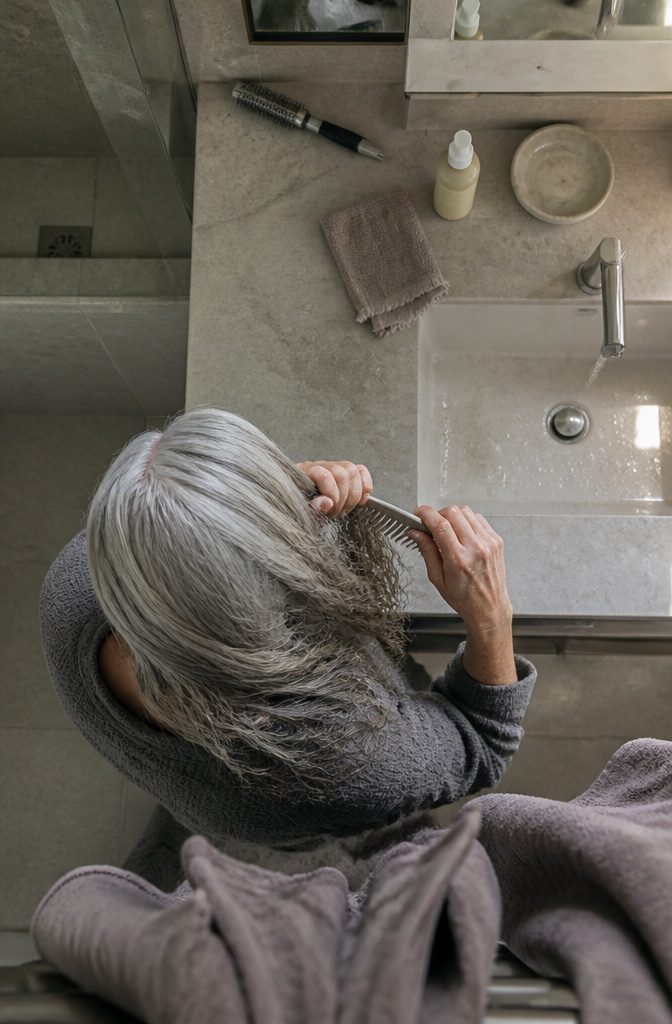 Gray hair beside a wide-tooth comb and heat protection product