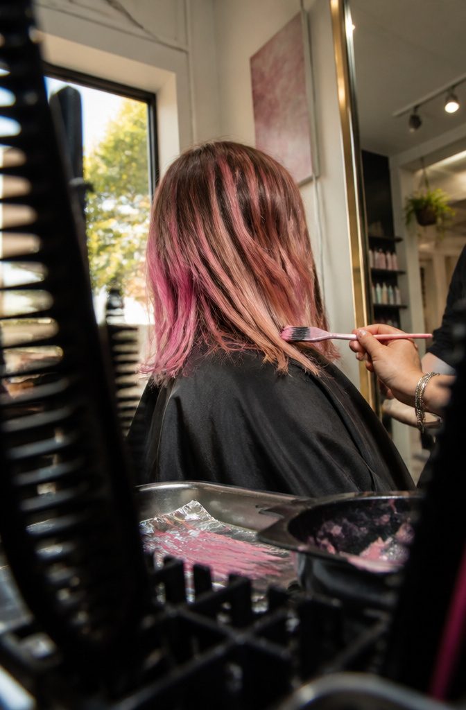 Pink highlights painted through hair with feathered ends and natural strands between