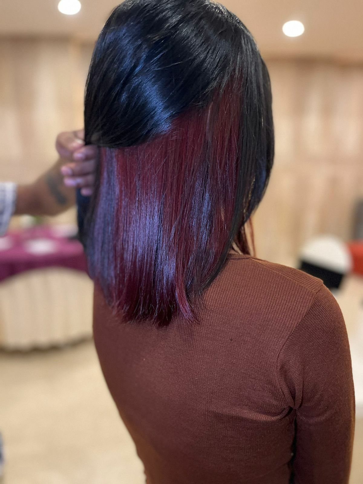Black bob with vivid red peekaboo strands revealed as a hand lifts the top layer