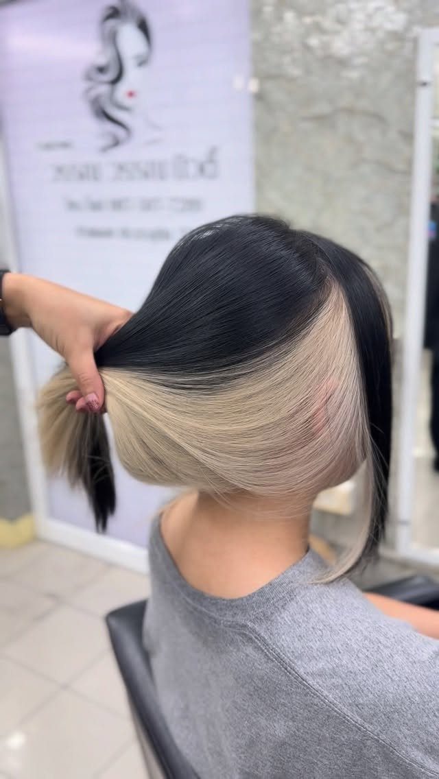 Dark hair swept aside to reveal a smooth pale blonde peekaboo underlayer