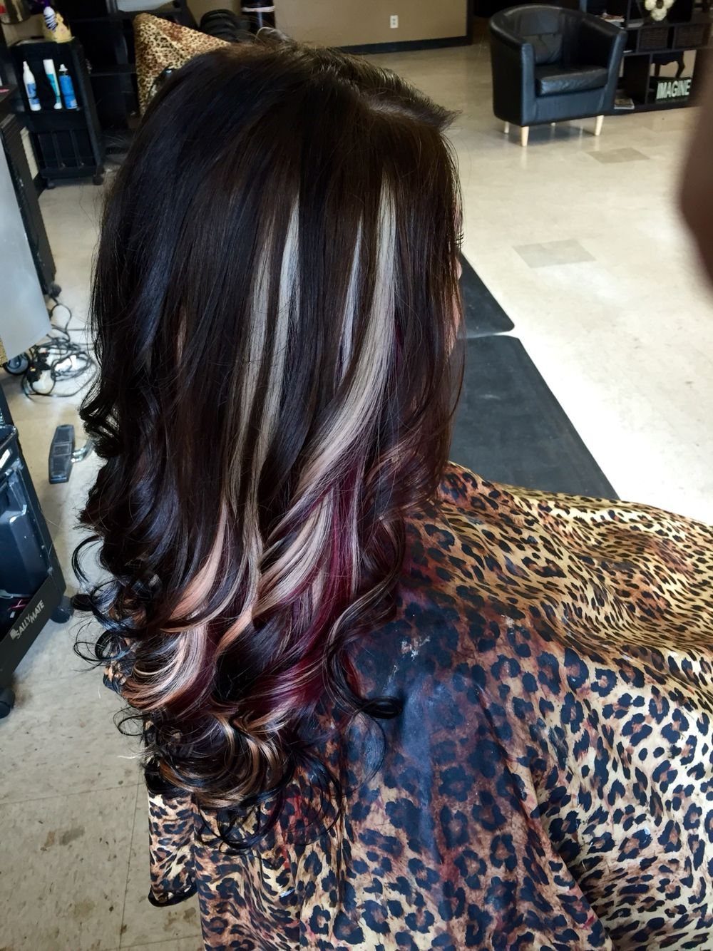 Dark brown curls reveal blonde and red-violet peekaboo streaks underneath.