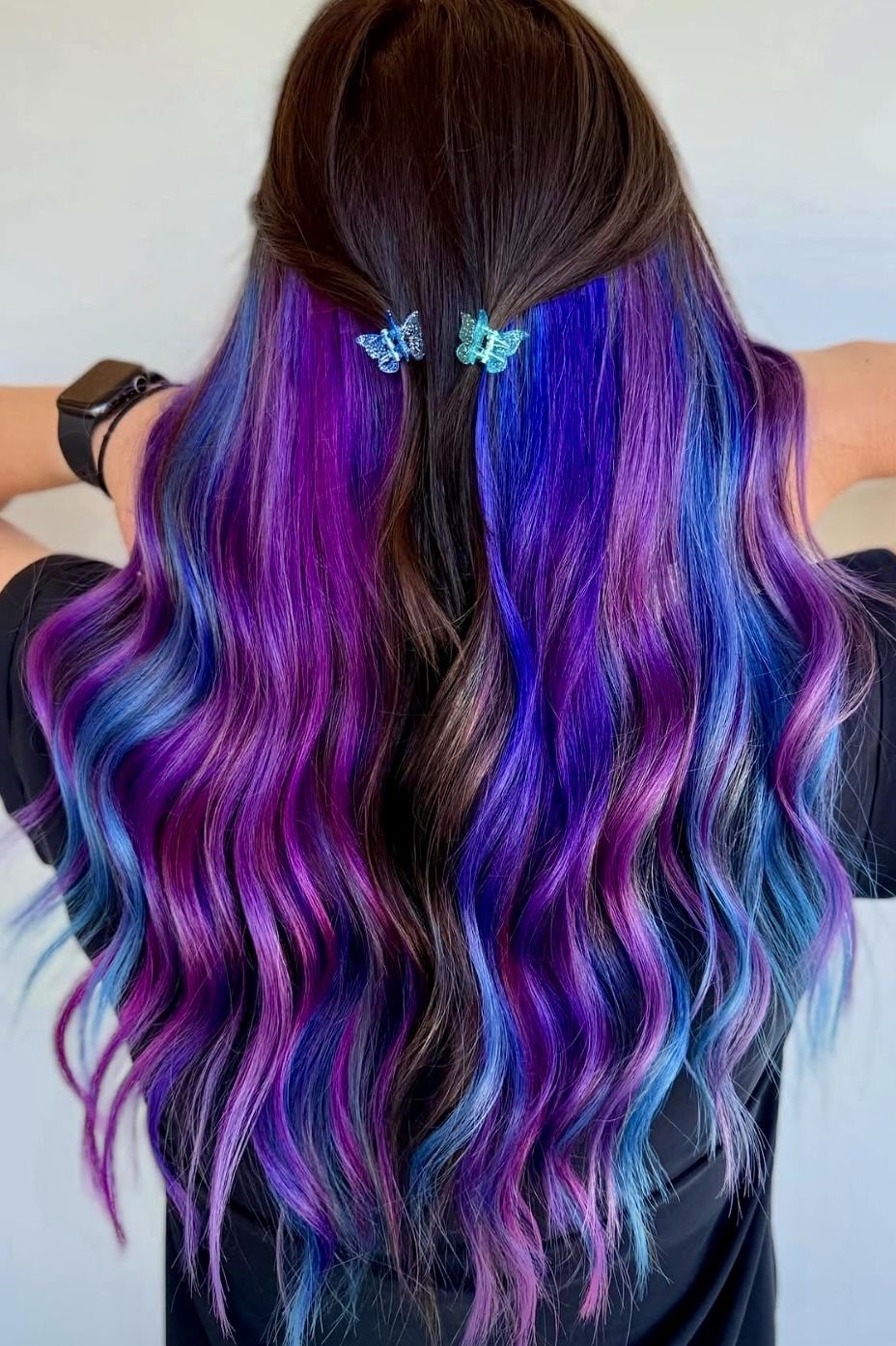 Half-up dark curls reveal vivid blue and violet peekaboo layers
