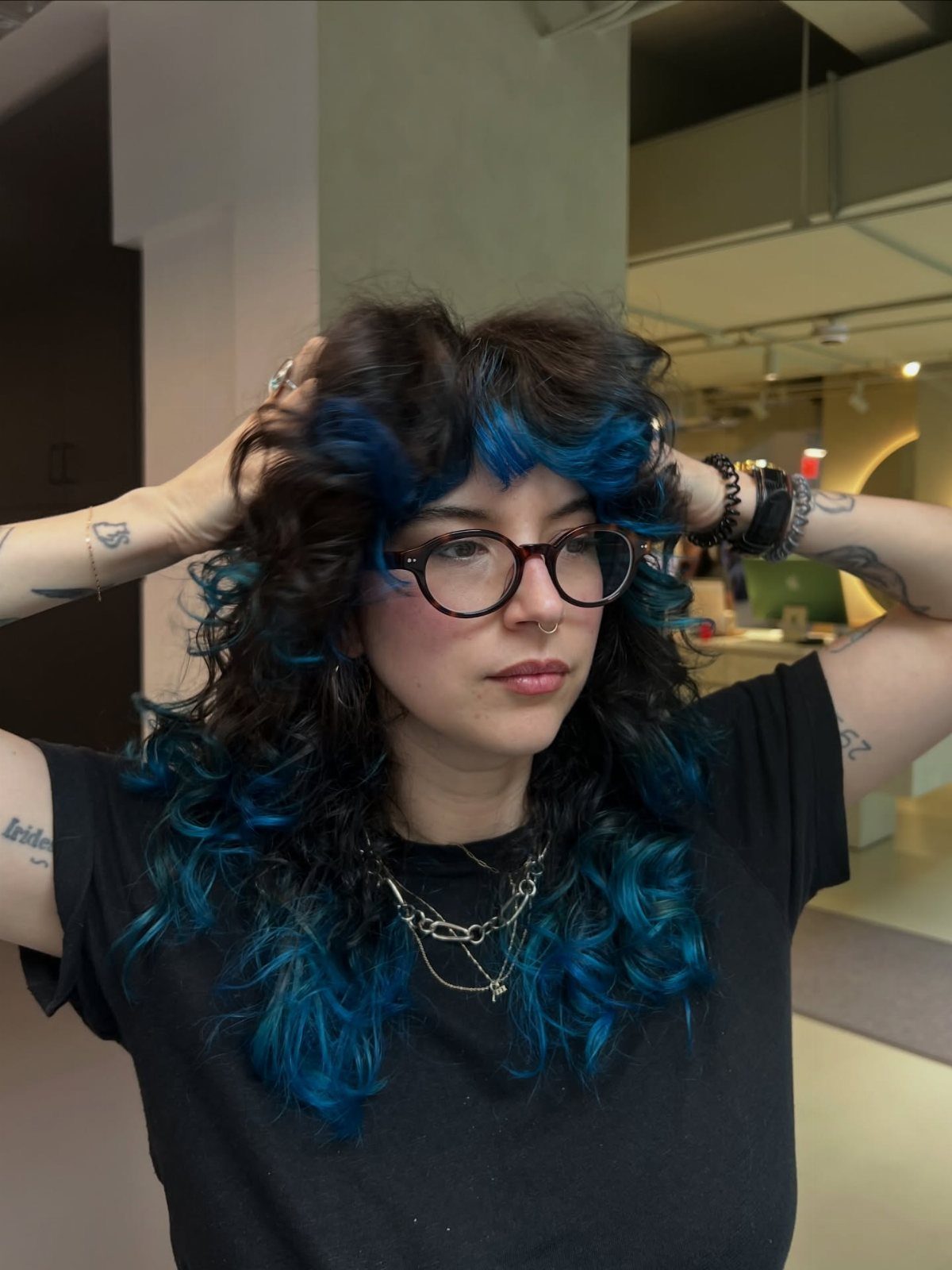 Curly-haired person showing vivid blue and teal color beneath dark curls
