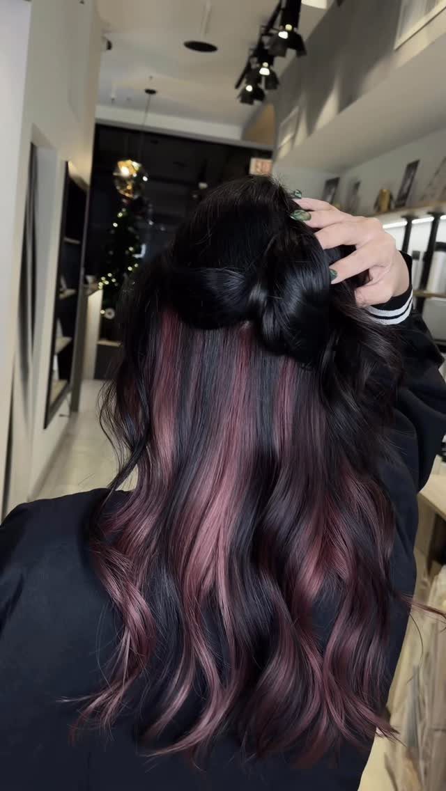 Wavy dark hair reveals hidden pink and purple underlayers in a salon