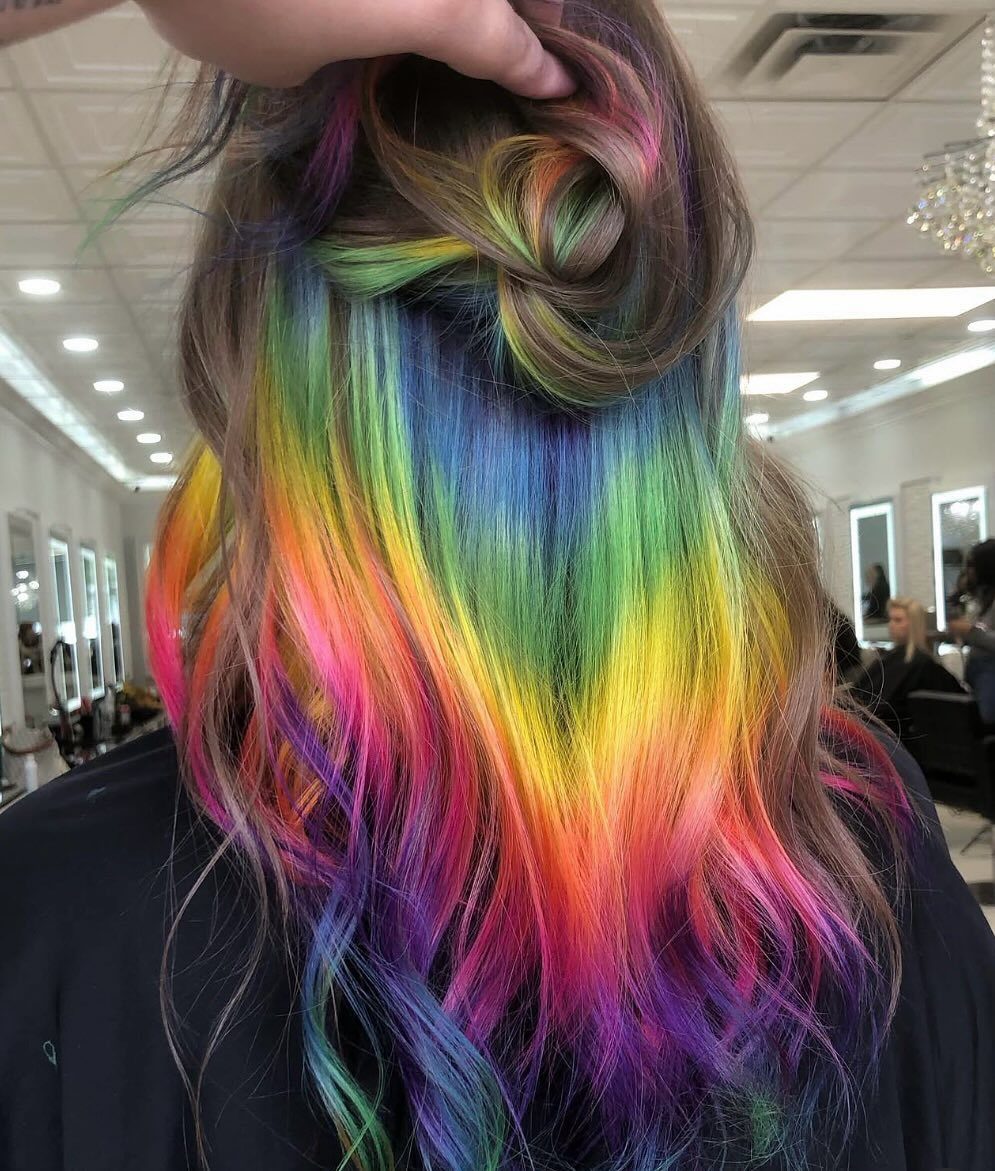 Dark brown hair lifted to reveal vivid rainbow peekaboo underlayers
