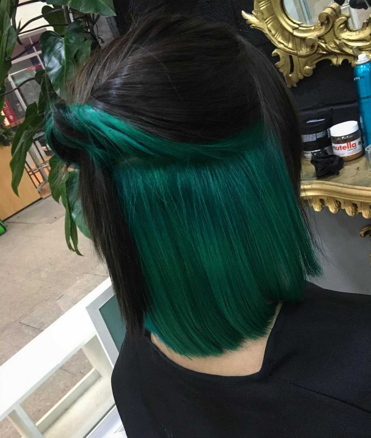 Dark bob reveals vivid green peekaboo underlayers swept across the back