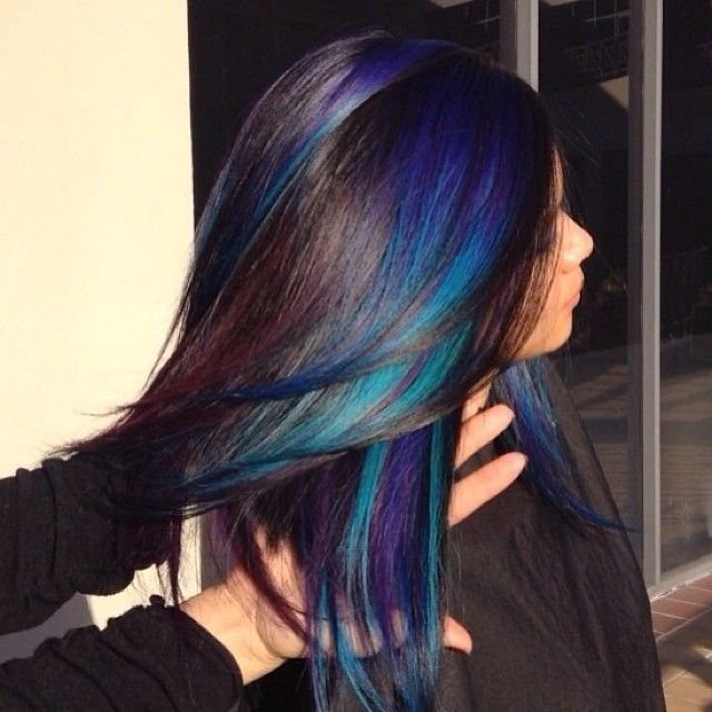 Long dark hair with blue, teal, and purple streaks spread to reveal jewel-toned layers