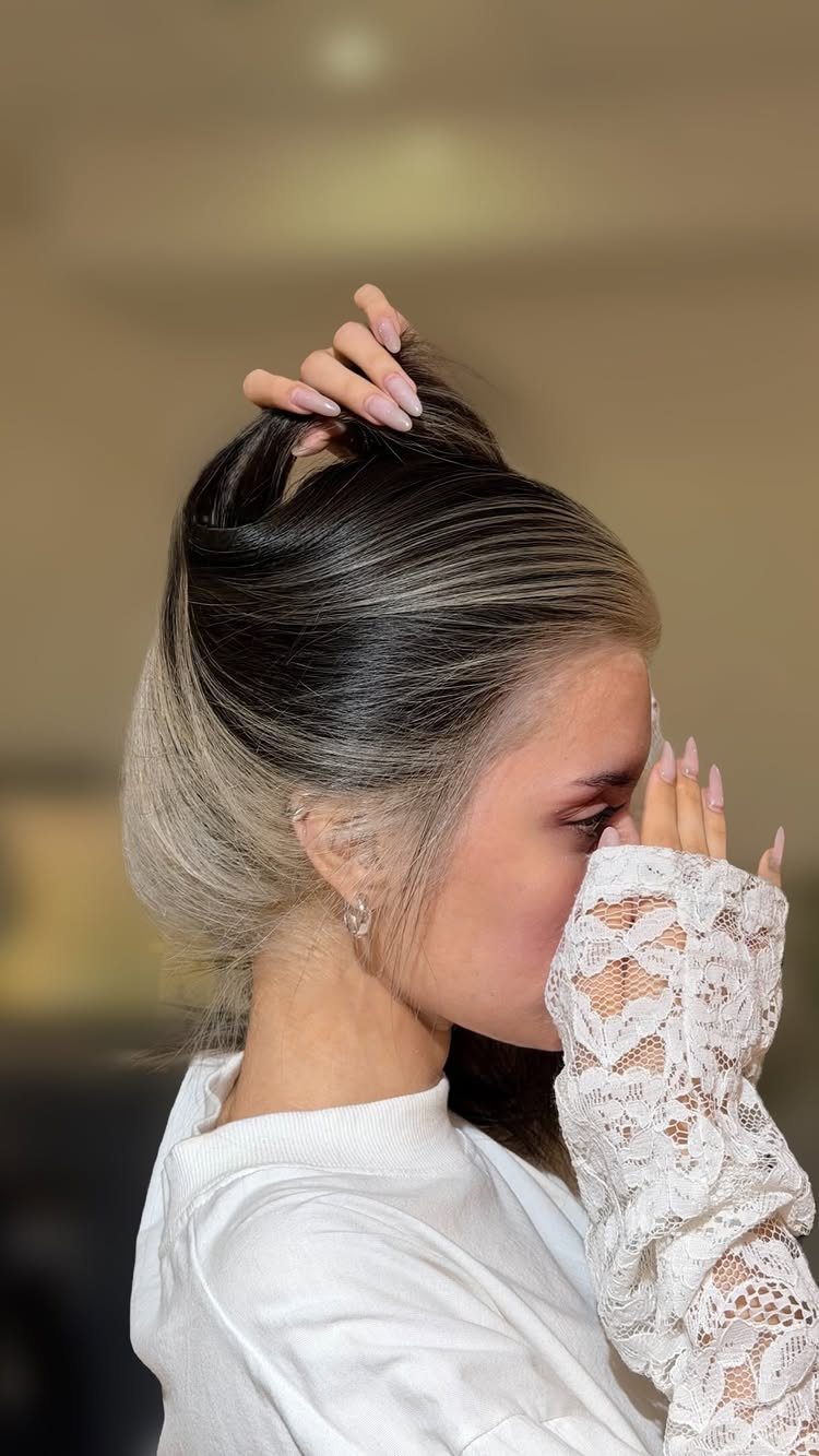 Woman lifts dark hair to reveal silver-gray peekaboo sections underneath