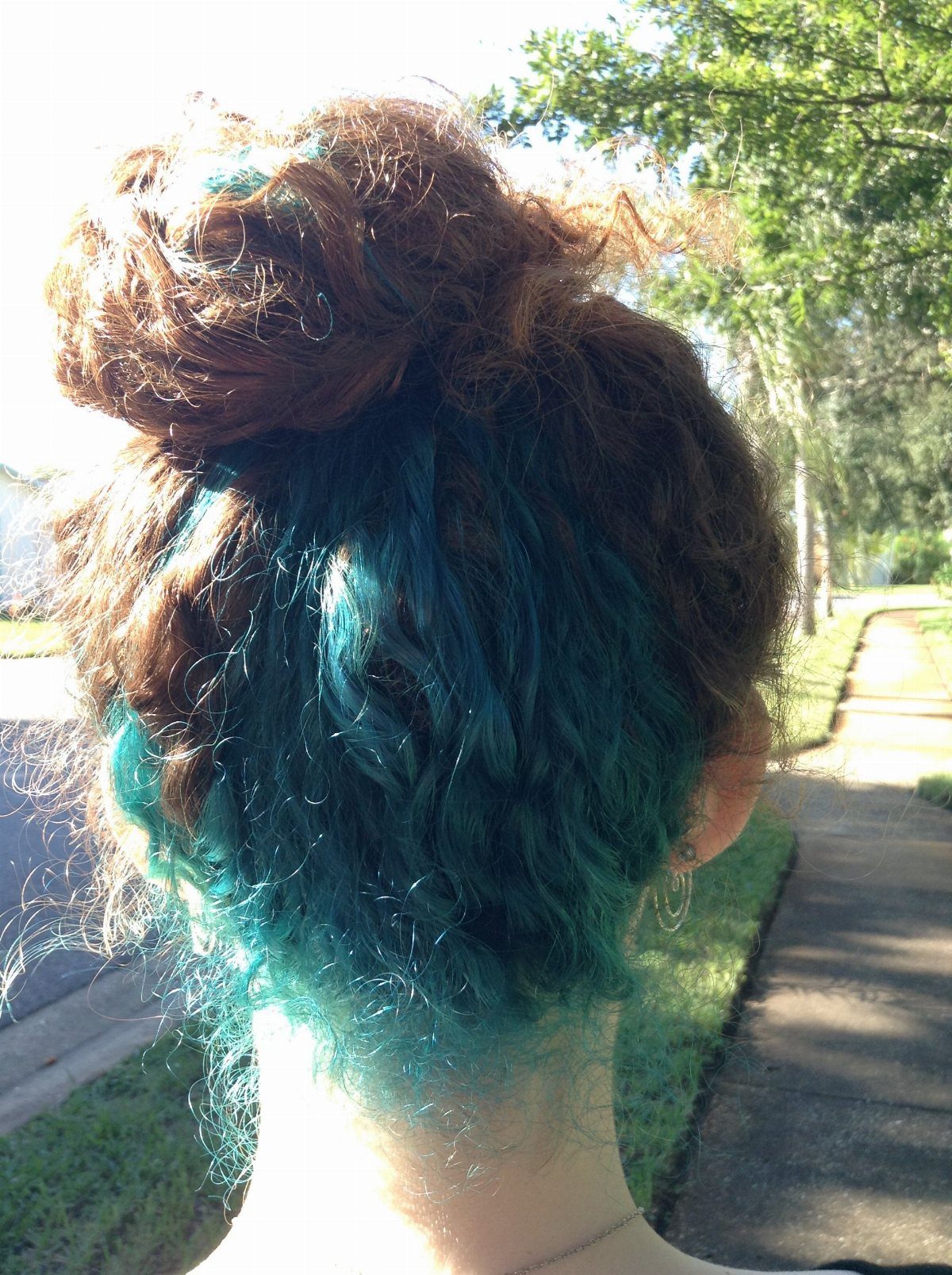 Teal curls gathered into a loose high bun with curls left loose at the nape