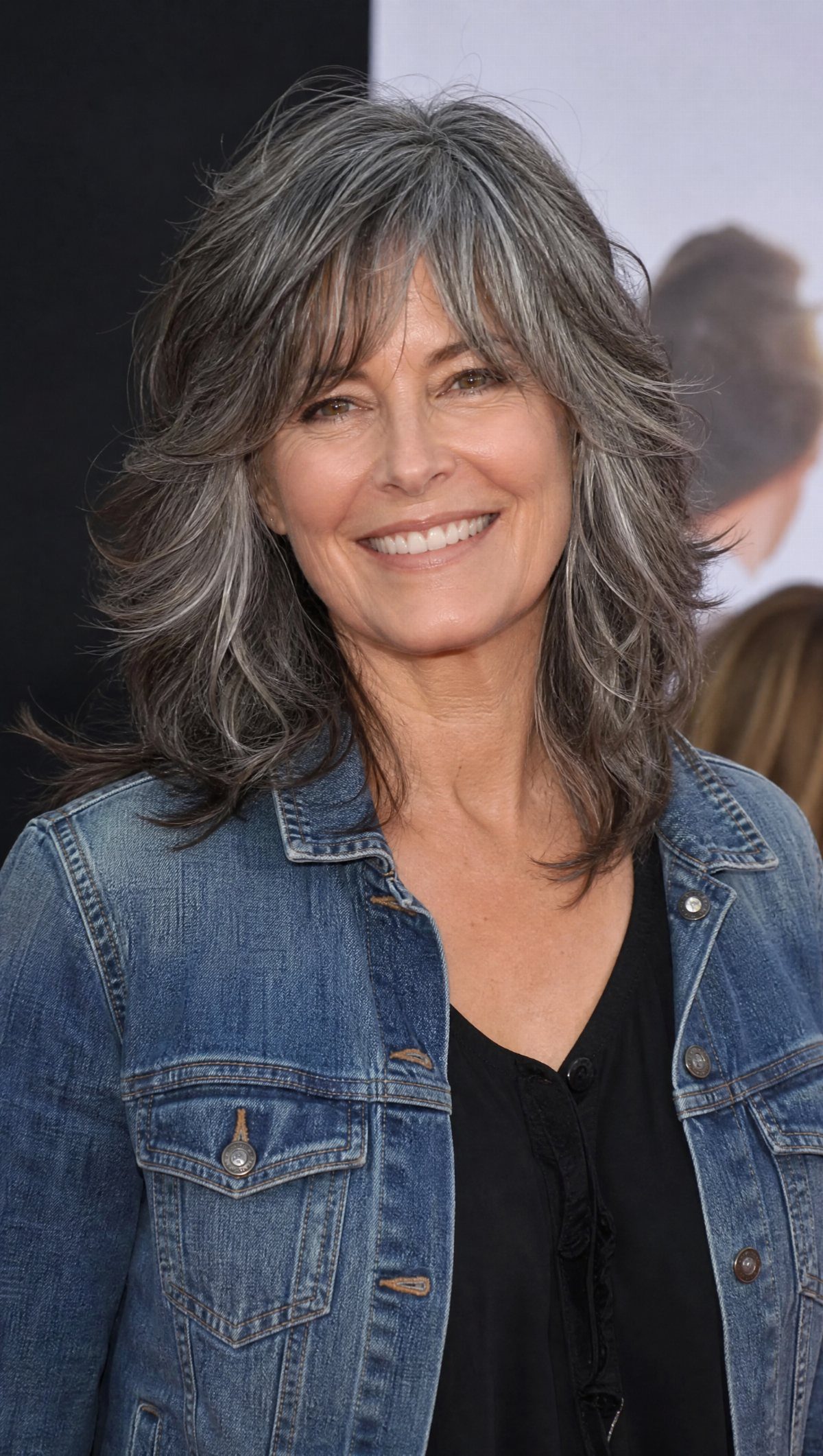 Woman with shoulder-length salt-and-pepper hair styled in soft feathered layers