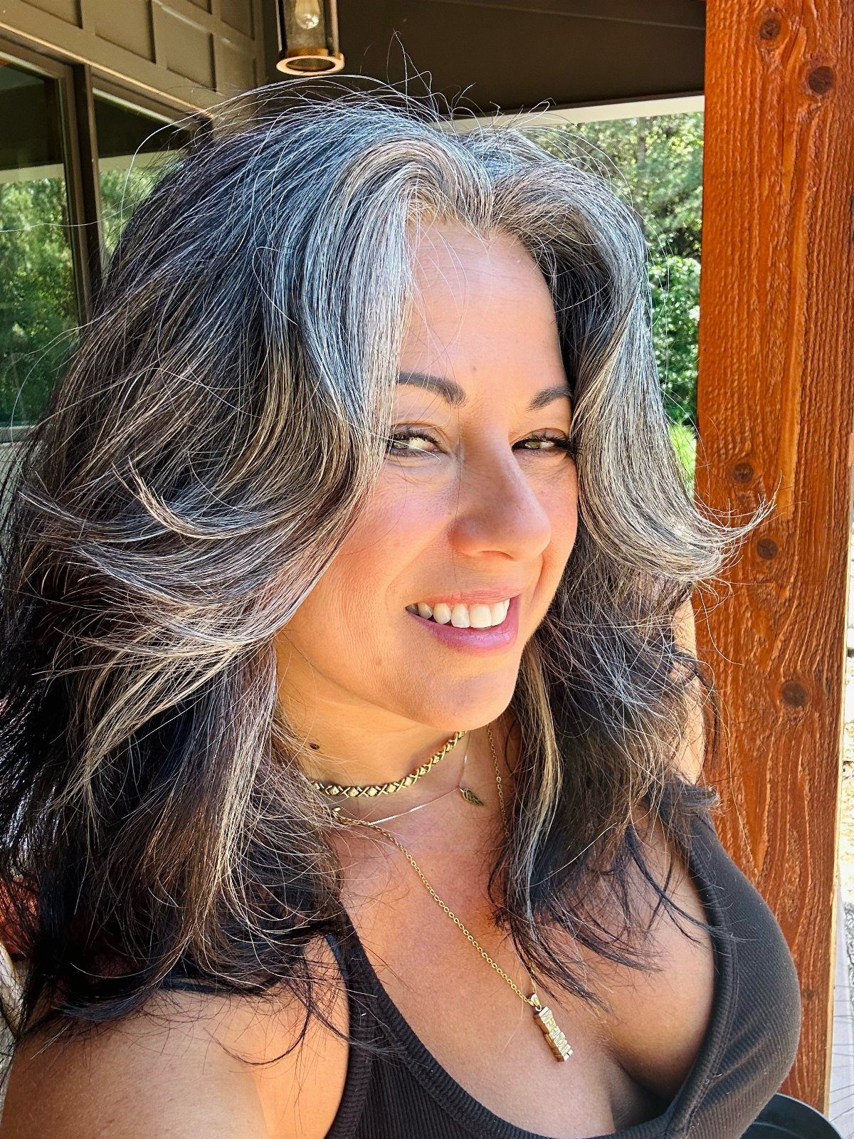 Woman with long layered salt-and-pepper waves and silver face-framing streaks