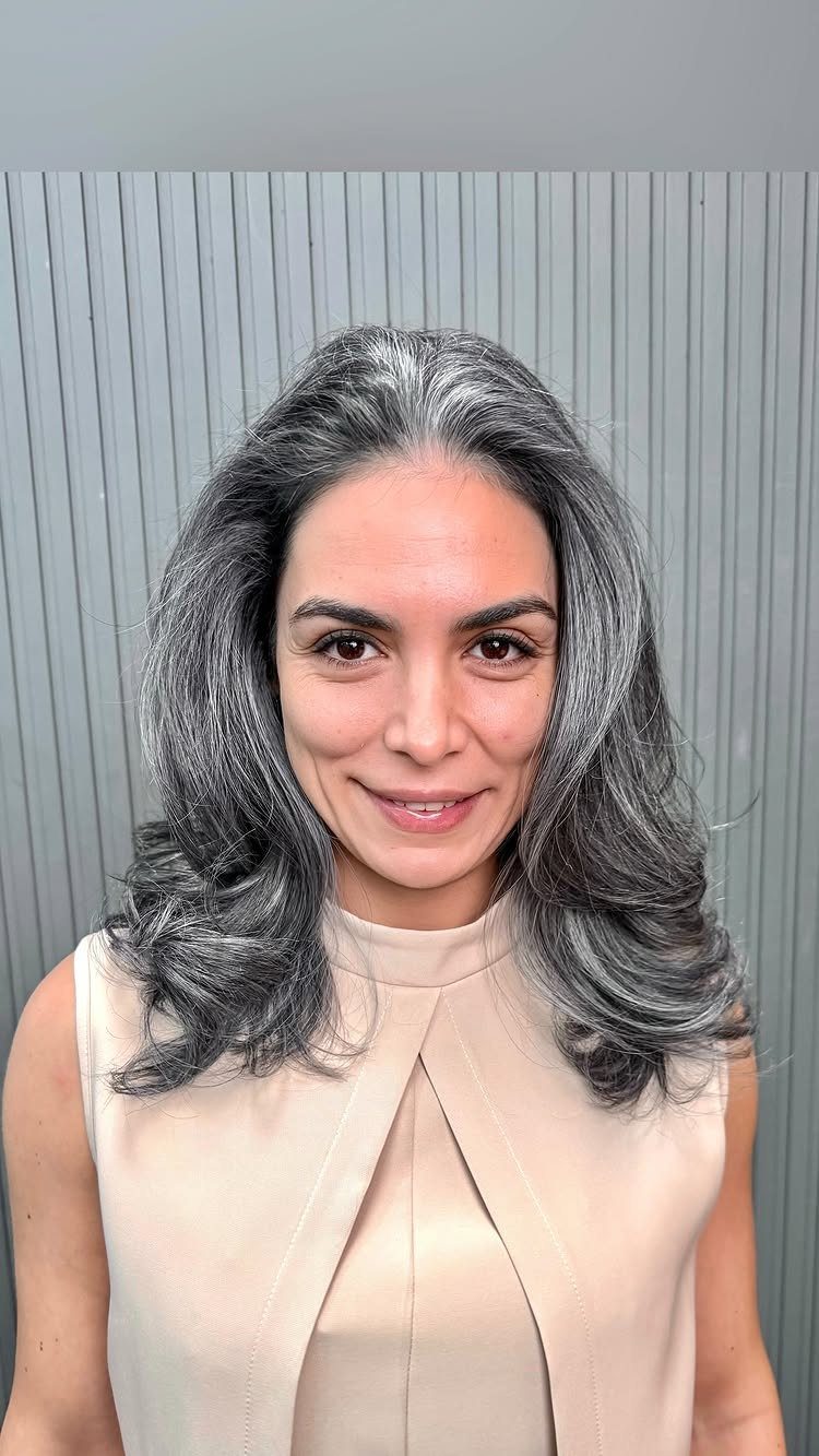 Woman with long dark hair and prominent silver-gray face-framing streaks