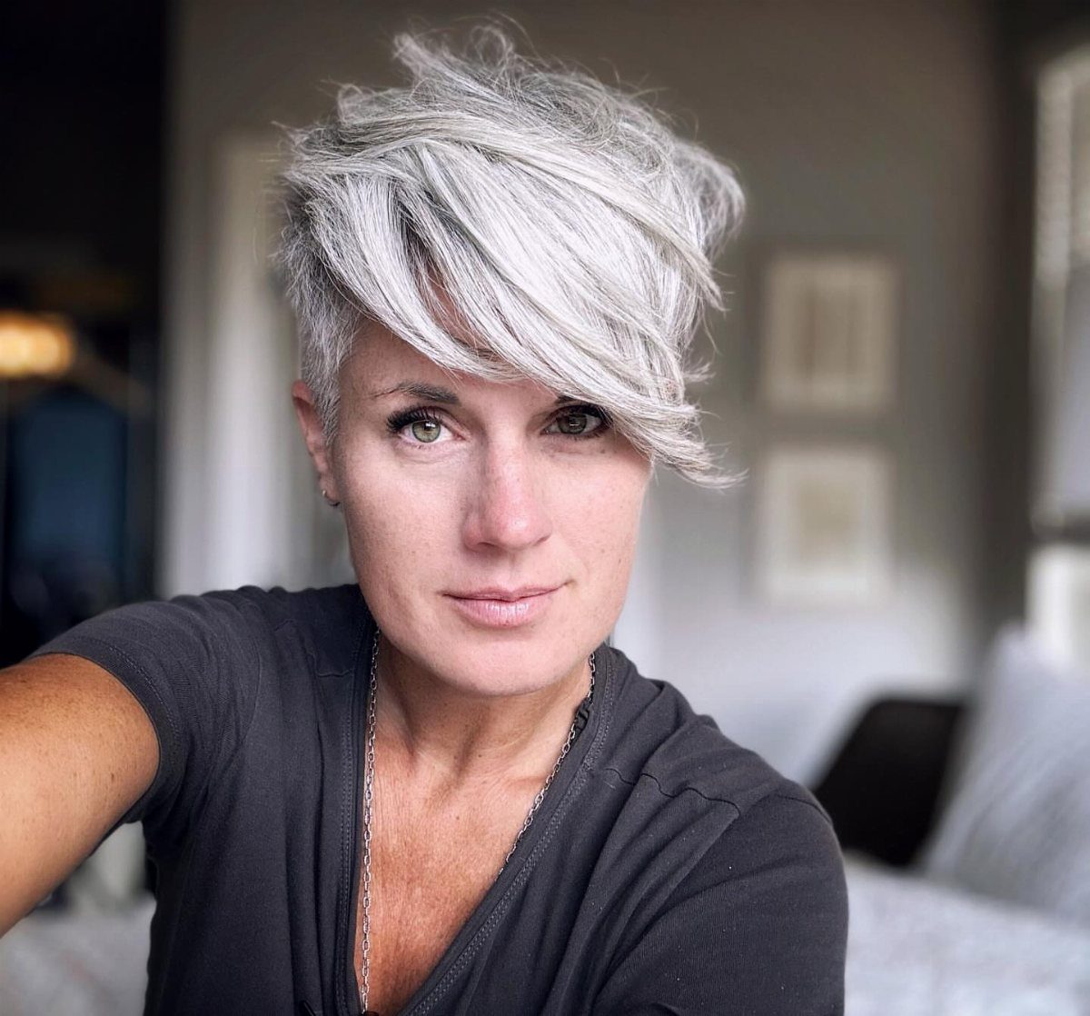 Woman with a textured silver pixie cut and darker strands swept across her forehead