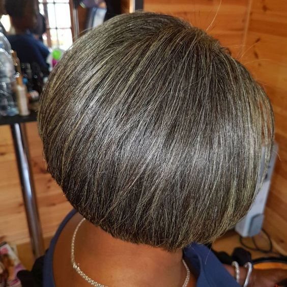 Short rounded bob blending silver-gray and dark strands in a salon