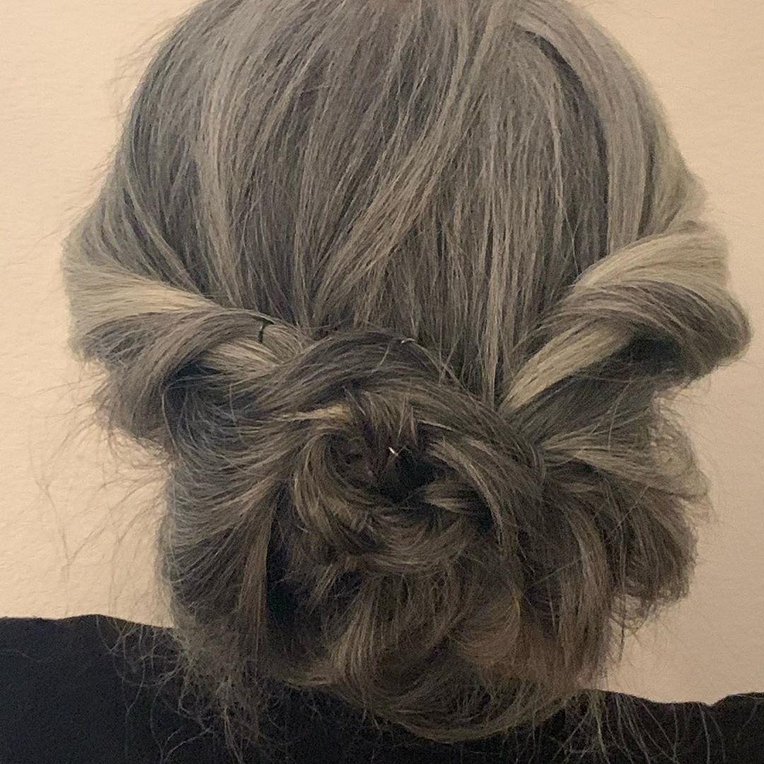 Salt-and-pepper hair arranged in a loose braided updo