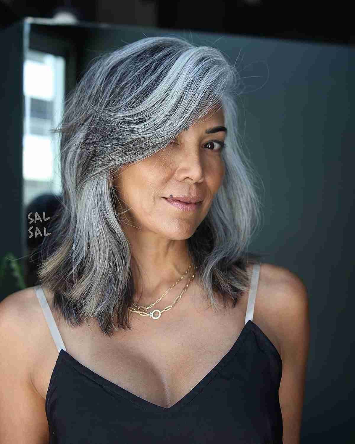 Woman with a shoulder-length salt-and-pepper bob and a sweeping side fringe