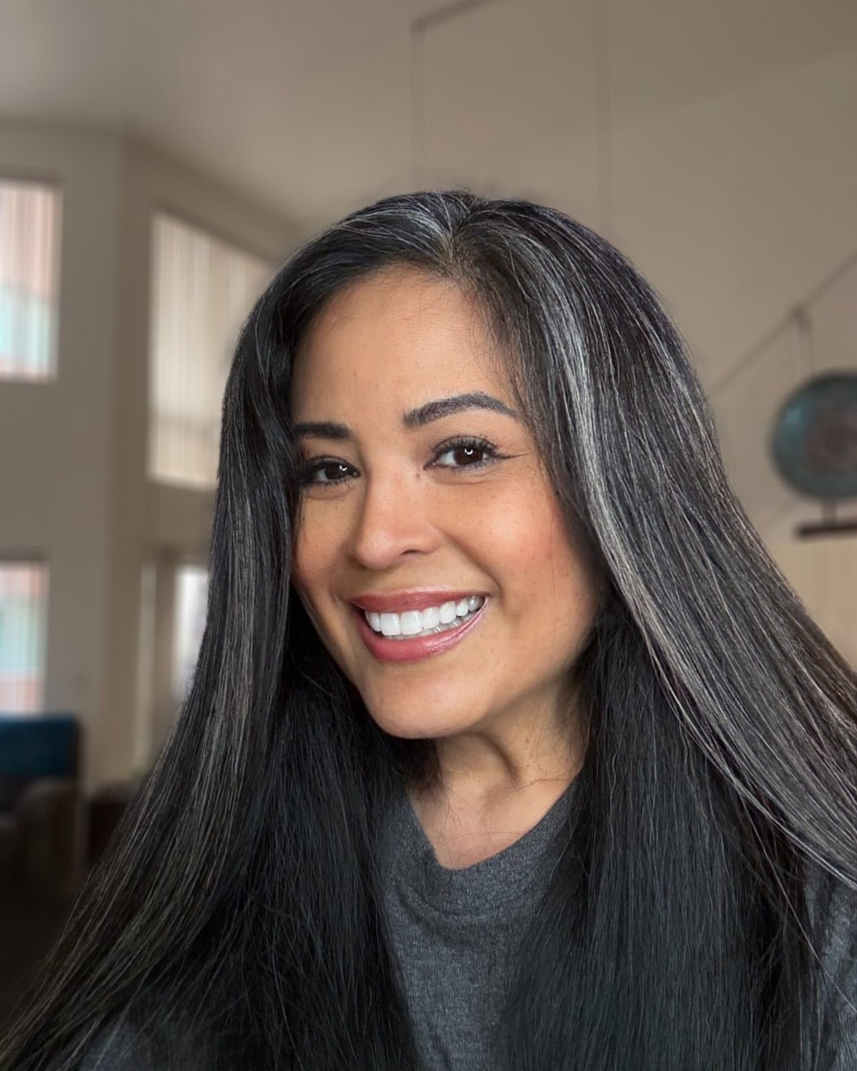 Woman with long dark hair and prominent silver-white streaks around her face