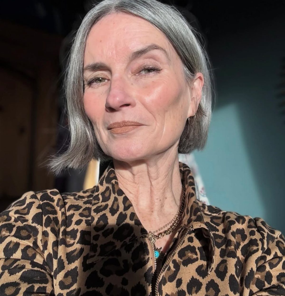 Older woman with a straight silver-gray bob and leopard-print blouse