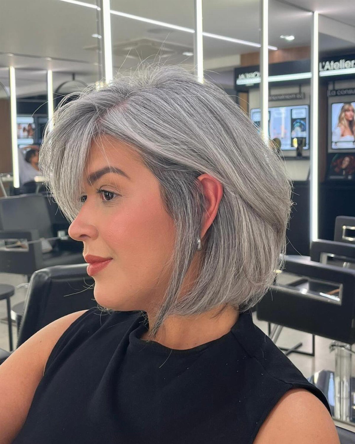 Woman with a layered silver-gray bob and side-swept fringe in a salon