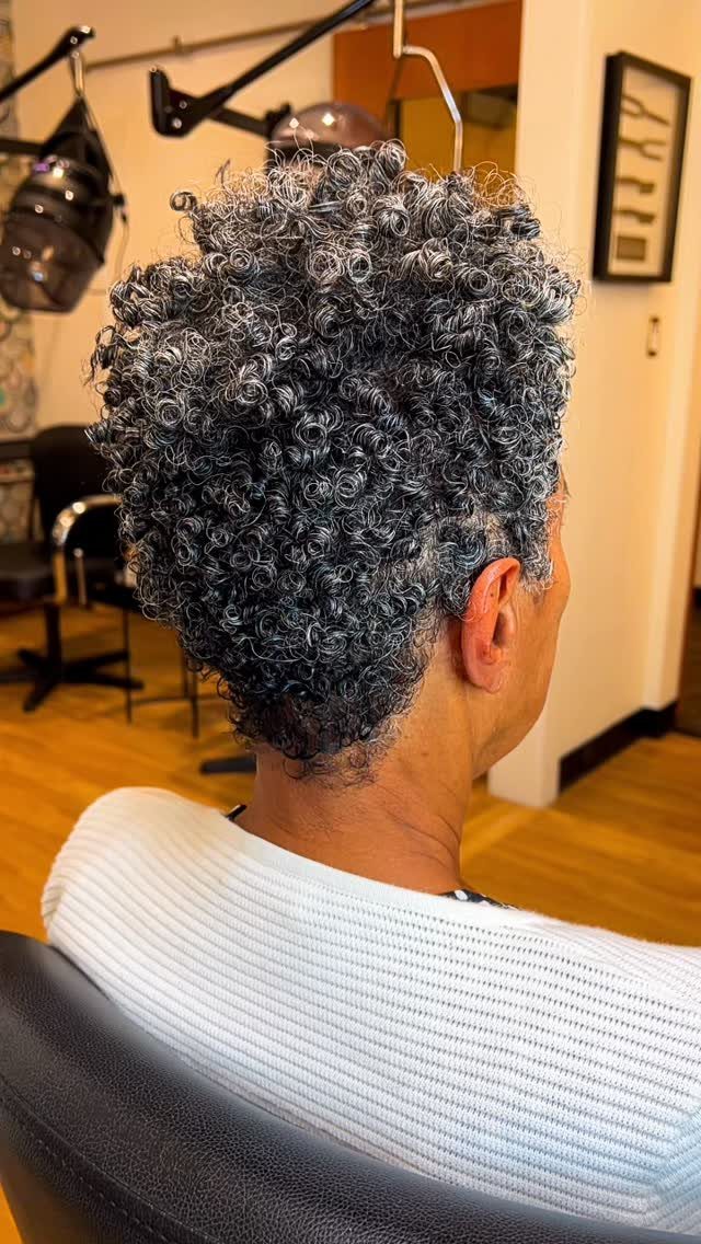 Short natural gray curls seen from behind in a salon chair