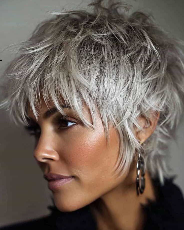 Woman wearing a tousled short silver-gray layered shag with wispy bangs
