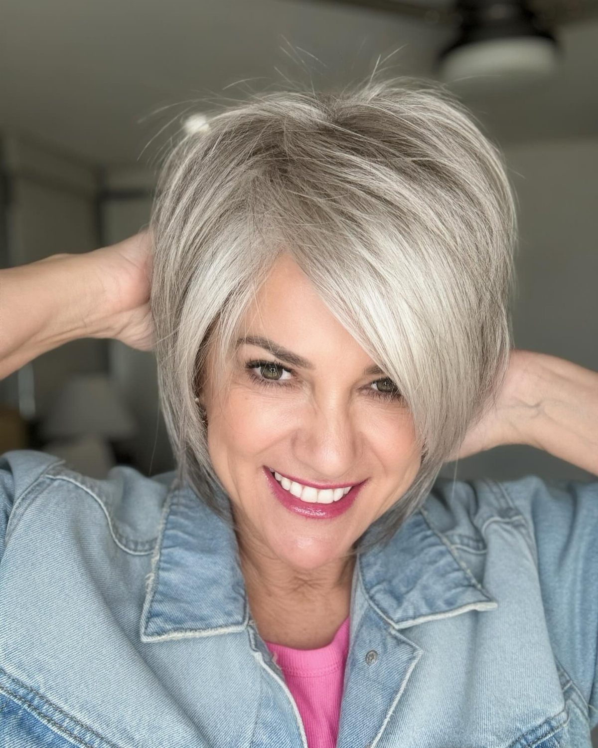 Woman with a side-swept silver-gray bob and soft bends, smiling in a denim jacket