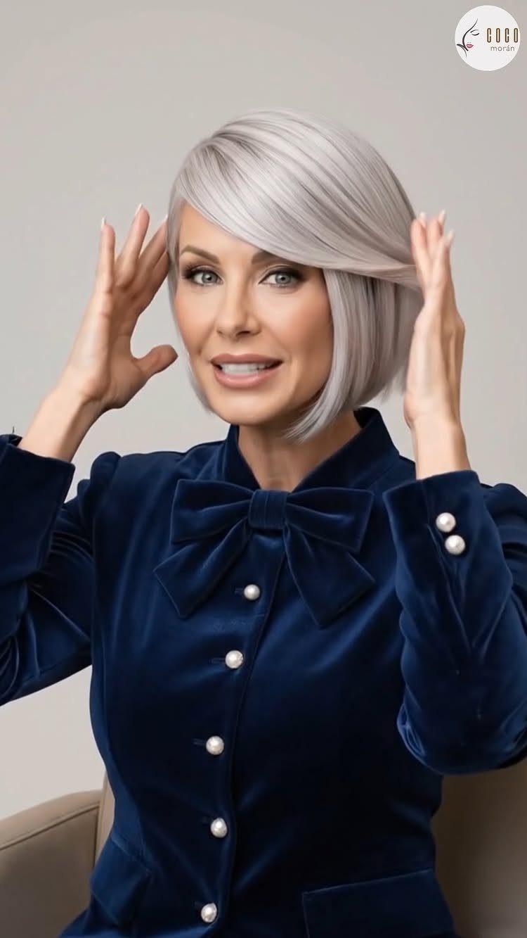 Woman posing with a sleek short silver-gray bob and side-swept bangs