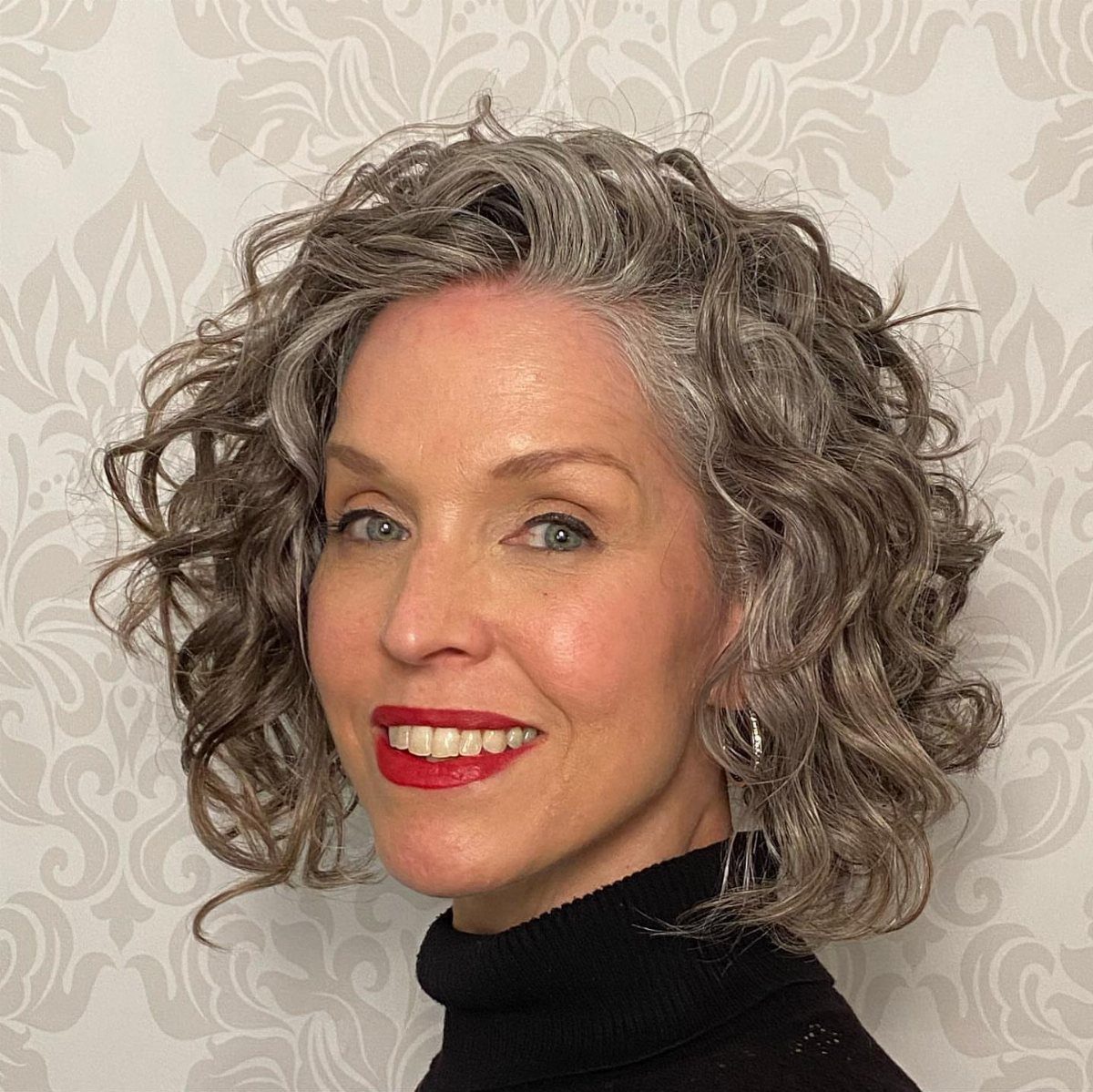 Woman with a voluminous gray bob styled in loose, textured curls