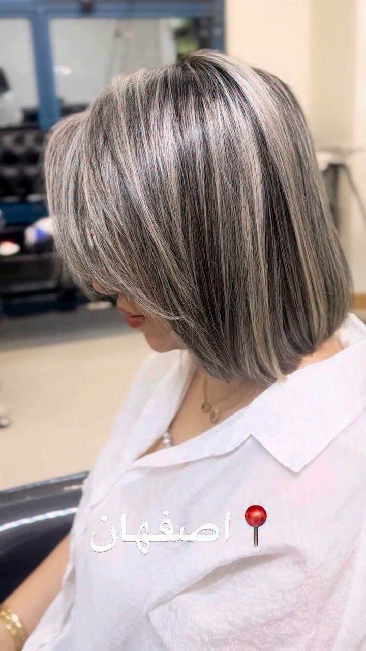 Woman with a sleek silver-grey bob haircut and dark streaks in a salon