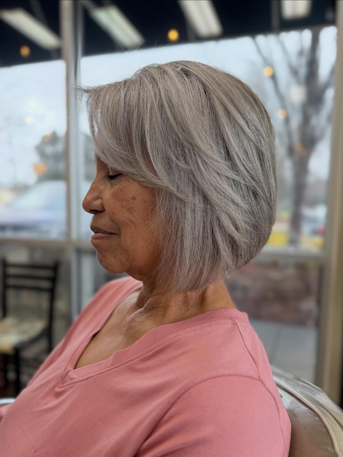 Woman with a softly layered silver-gray bob and side-swept bangs in profile