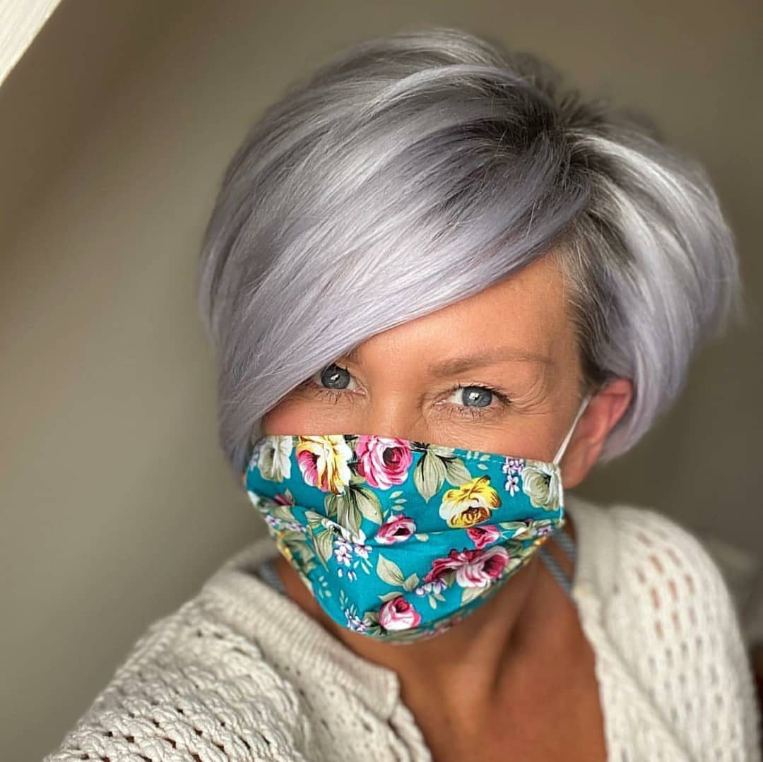 Older woman with smooth side-swept silver-gray bob and colorful floral face mask