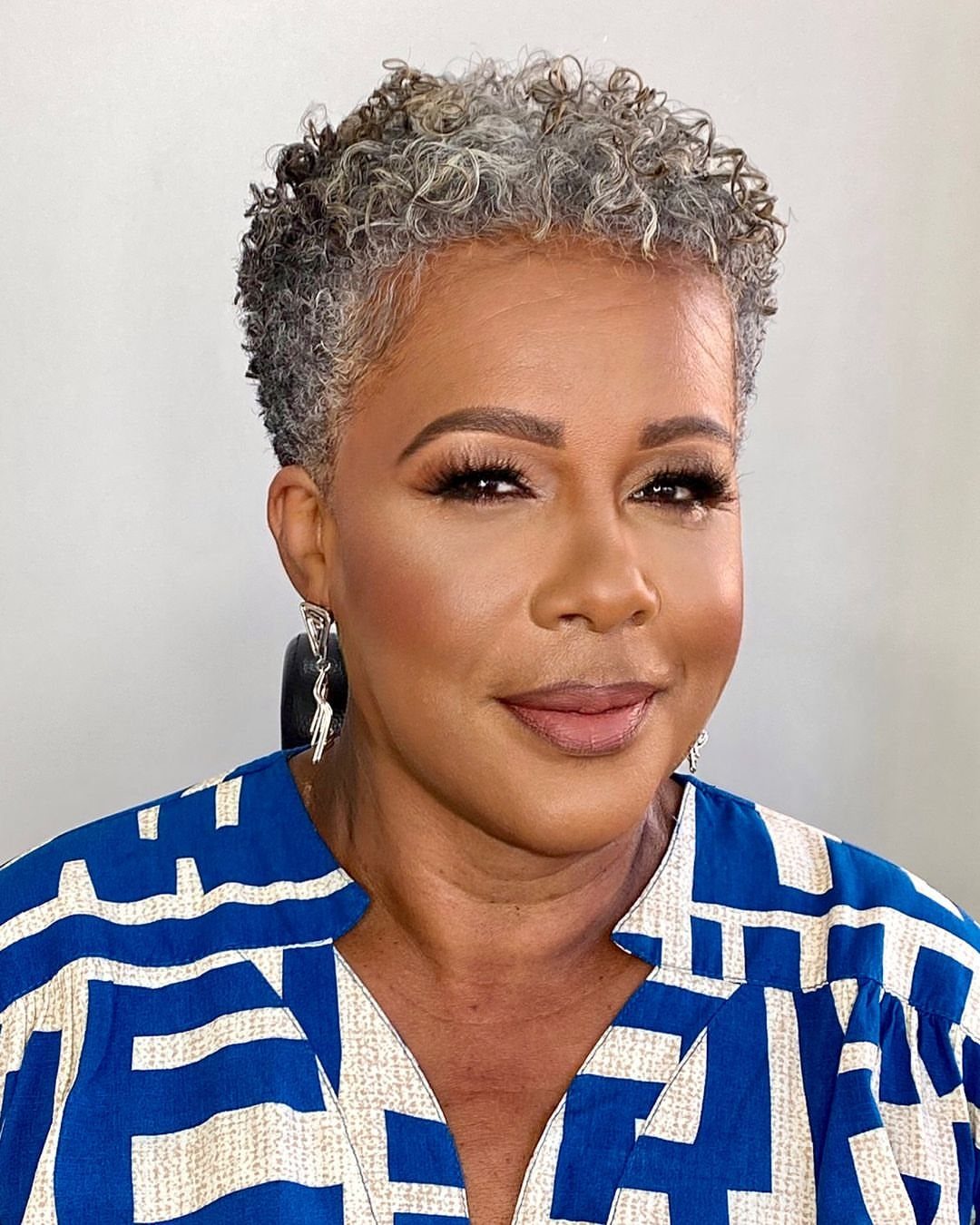 Woman with short, tightly curled gray hair and a blue patterned top