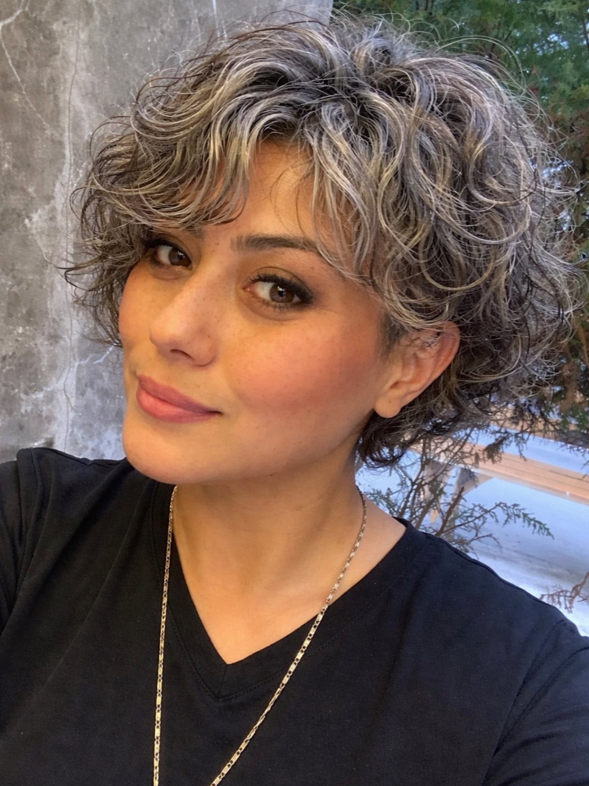 Woman with tousled silver-gray curls in a short, side-parted hairstyle