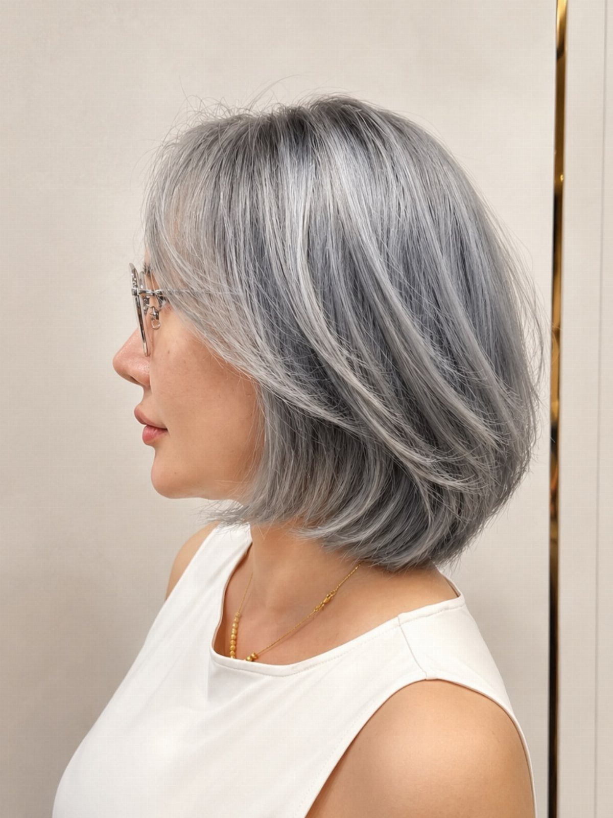 Woman with a textured silver-gray bob and feathered ends viewed in profile