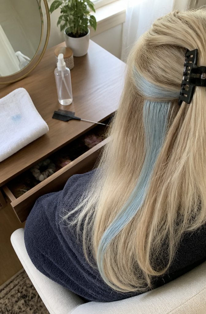 Pale blue streak in blonde hair with remaining hair clipped back