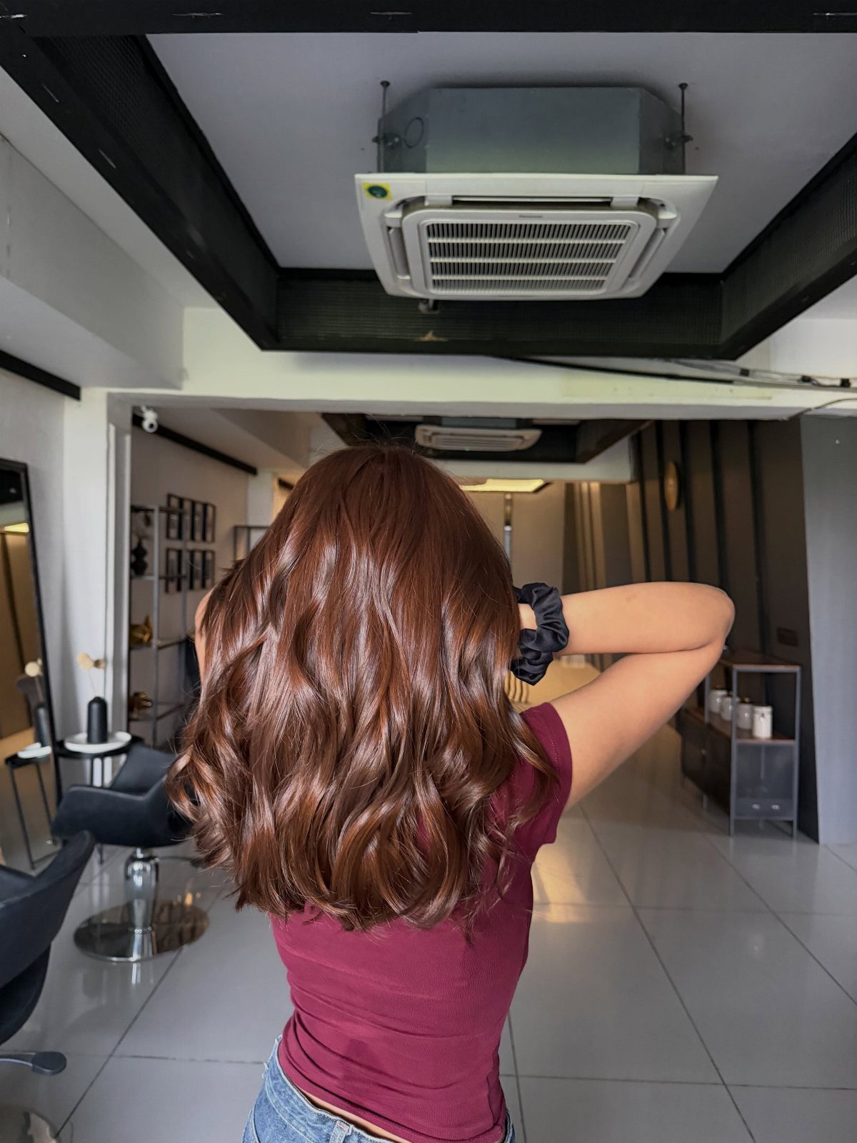 Wavy auburn-brown hair shown from behind in a salon