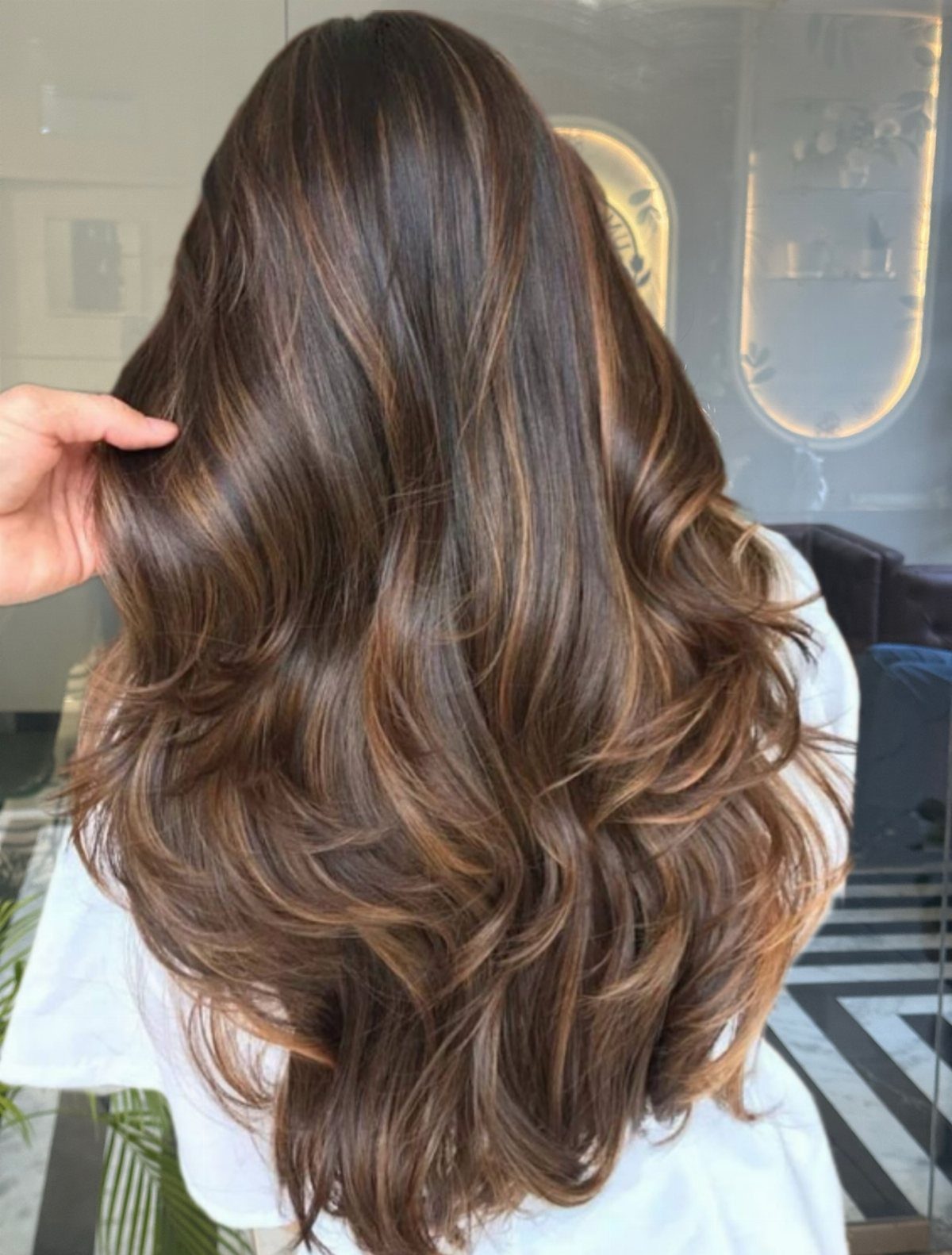 Long wavy brunette hair with blended caramel balayage highlights in a salon