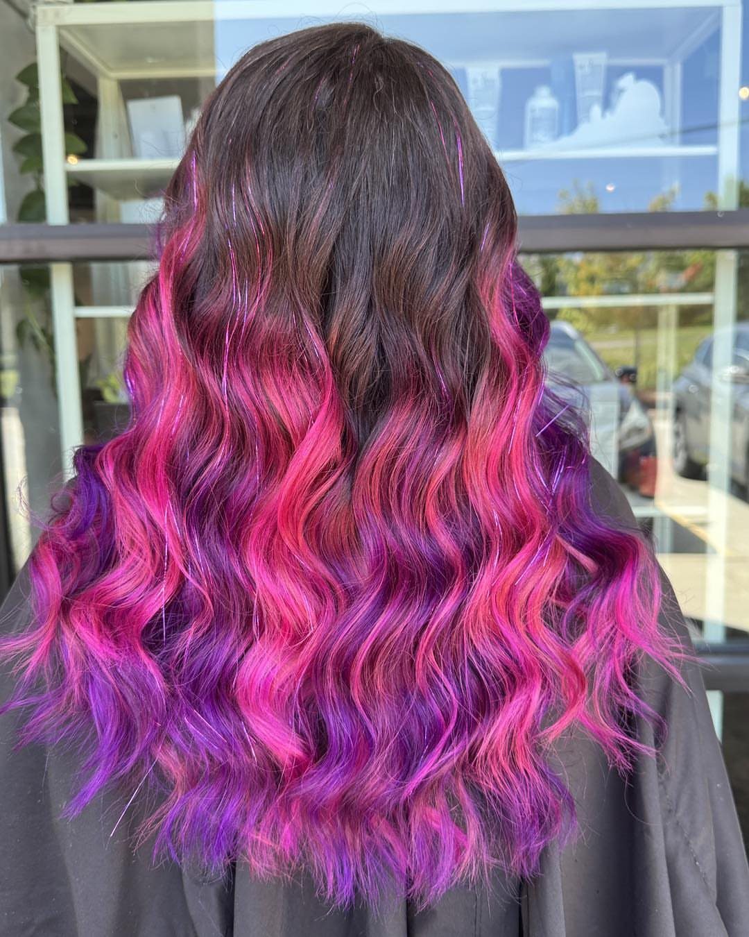 Long wavy hair with bright pink and purple color fading through dark brown lengths