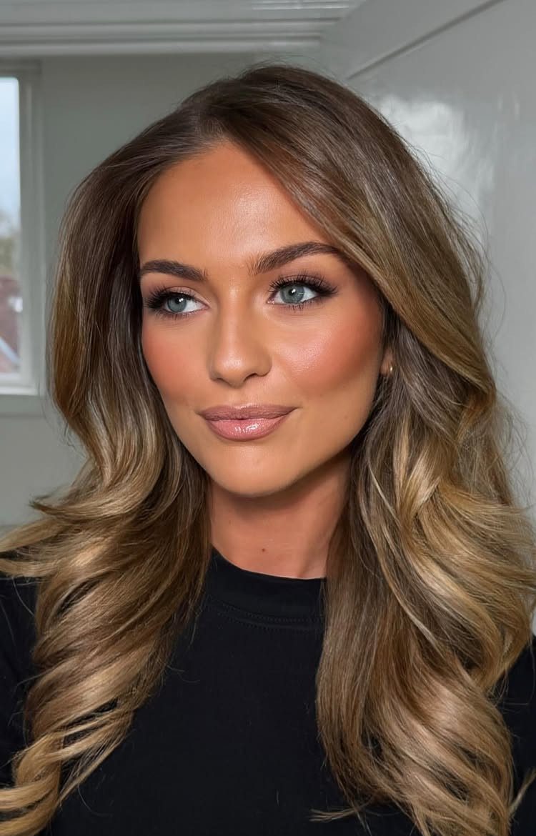 Woman with long, warm bronzed blonde hair and lighter face-framing highlights