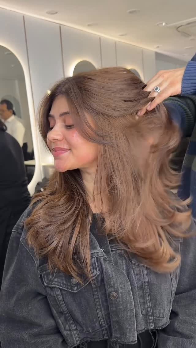 Warm brown hair with caramel-toned strands styled in long, voluminous layers