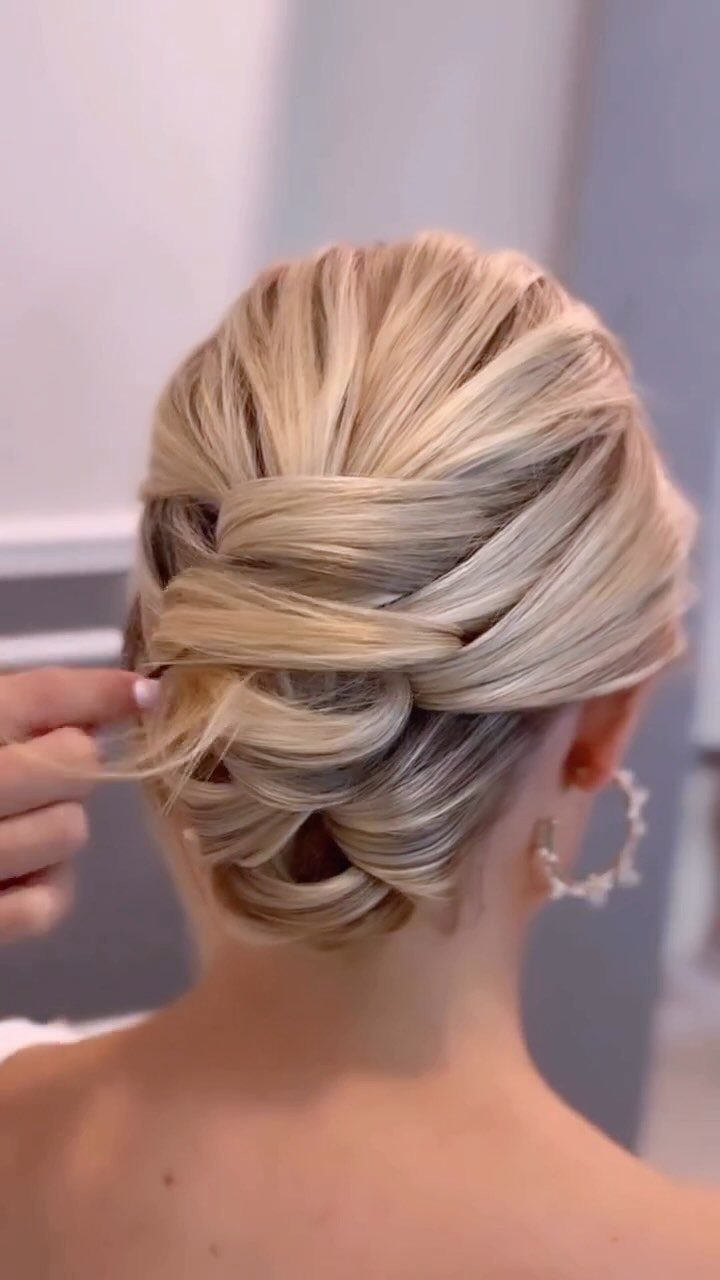 Blonde hair styled into a loose, intricately wrapped bohemian updo