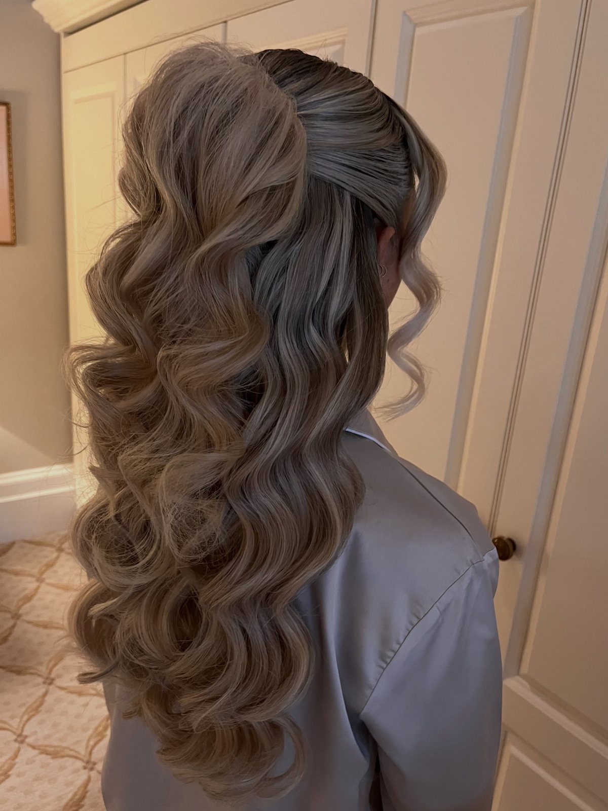 Long brown half-up hair cascading in loose curls over a pale satin robe