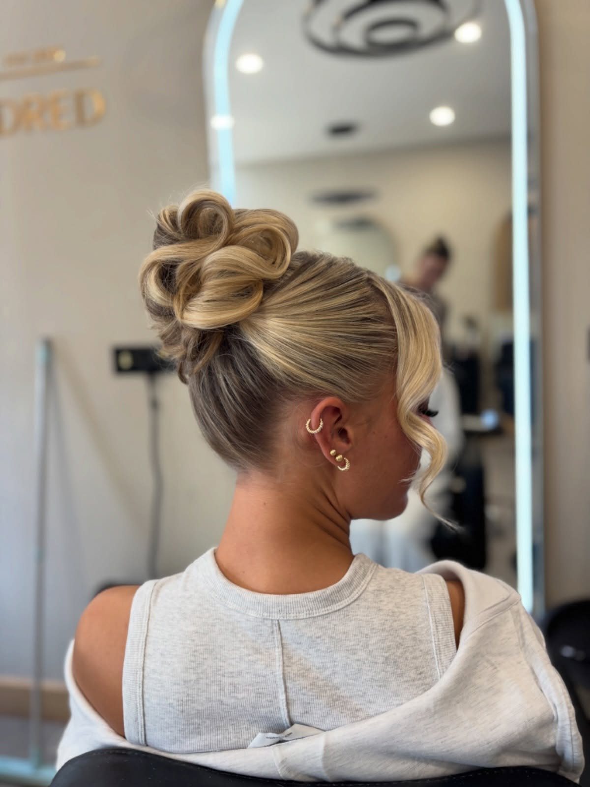 Blonde twisted updo with a loose face-framing curl in a salon