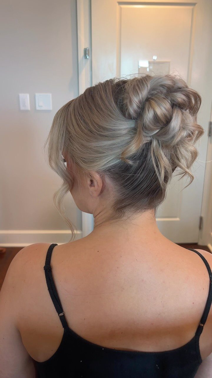 High sculpted updo with smooth sides and curled loops at the crown
