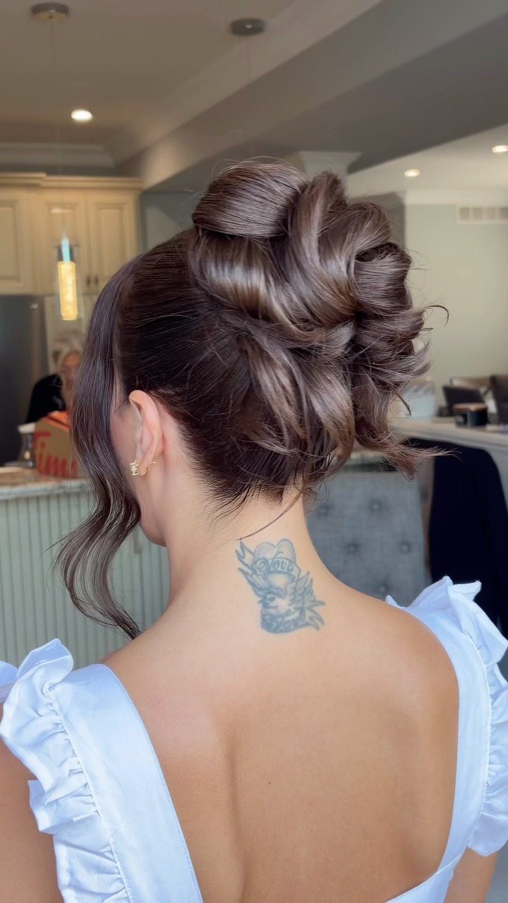 Tousled brown updo with loose curled front strands on a woman in a pale blue dress