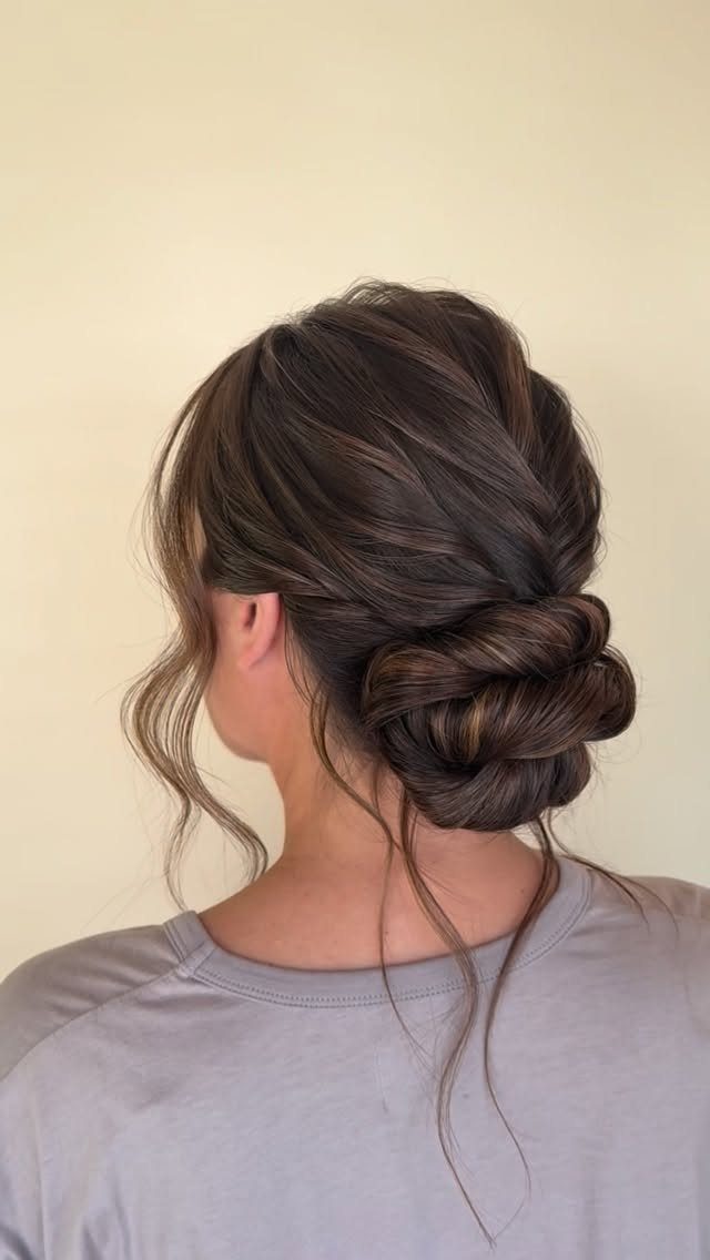 Twisted dark hair gathered into a low bun with loose tendrils