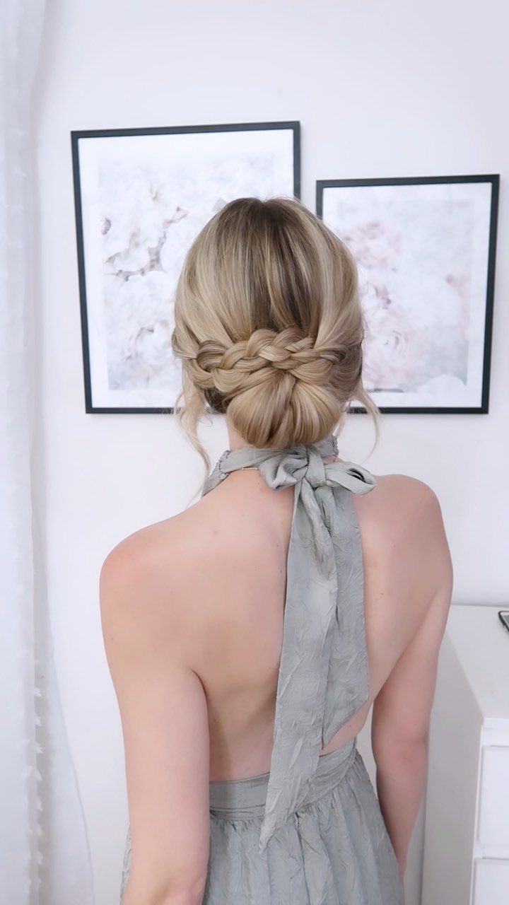 Blonde braided updo gathered into a low bun with a gray ribbon