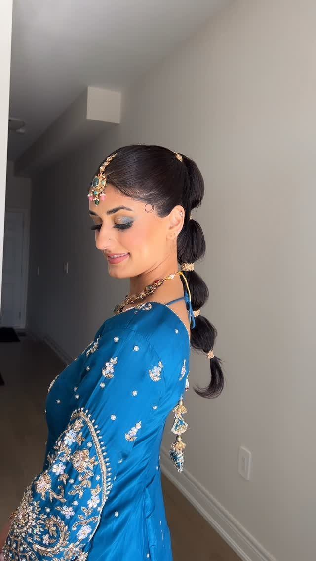 Woman in blue wearing a bubble ponytail with gold bands and jeweled ornaments