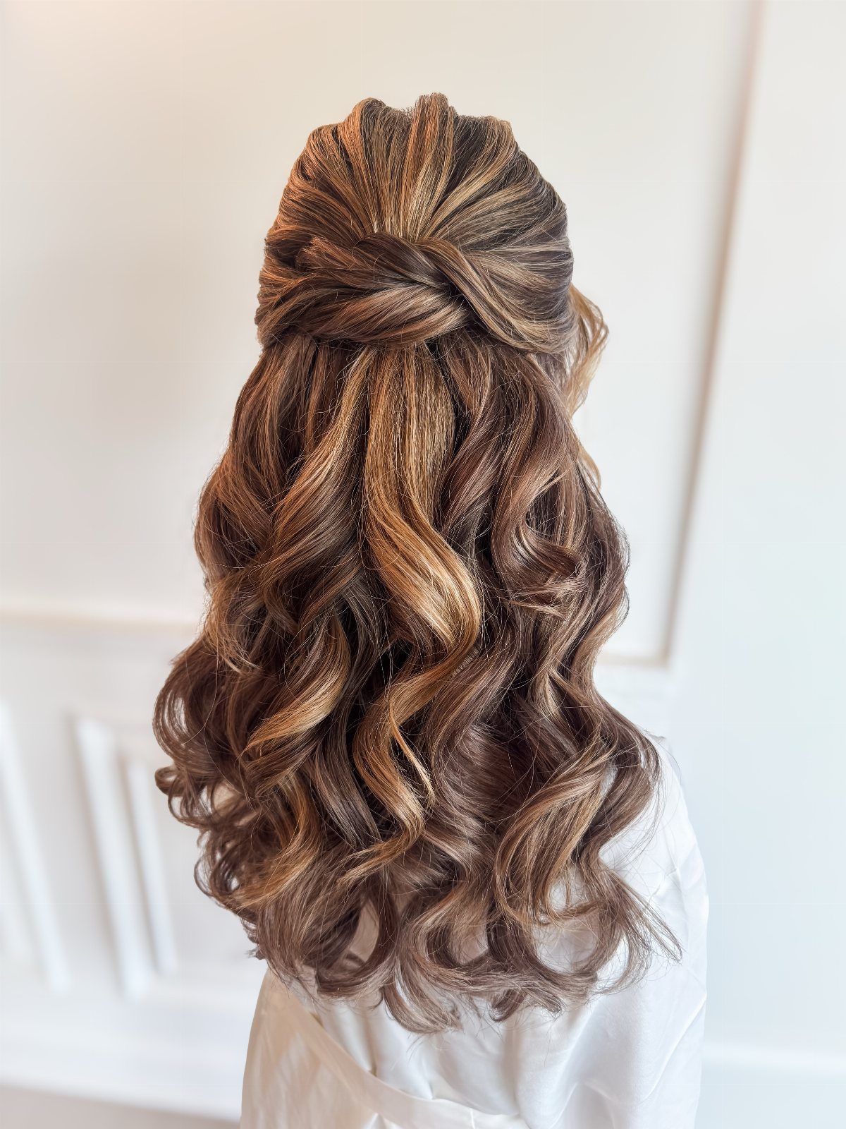 Long brown hair with loose curls and a twisted half-up section cascading down