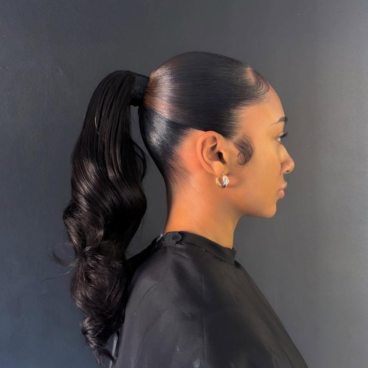 Woman wearing a sleek high ponytail with long glossy curls